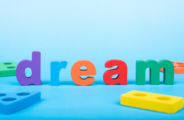 Dream word written with wooden alphabets blocks on blue chart kids children background