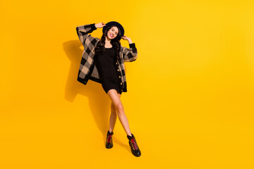 Obraz na płótnie Canvas Full length photo of stunning happy positive young lady wear plaid coat mini black dress hat isolated on yellow color background