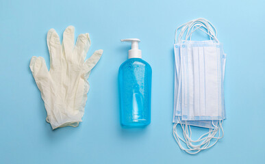 Latex gloves, hand sanitizer and medical masks on a blue background. Top view