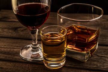 Three glasses with brandy, tequila and red wine on an old wooden table. Angle view