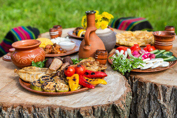Homemade Romanian Food with grilled meat, polenta and vegetables Platter on camping. Romantic traditional Moldavian food outside on the wood table.