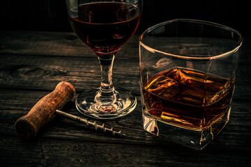 Glass of brandy and red wine with corkscrew on an old wooden table. Angle view