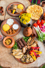 Homemade Romanian Food with grilled meat, polenta and vegetables Platter on camping. Romantic traditional Moldavian food outside on the wood table.