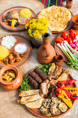 Homemade Romanian Food with grilled meat, polenta and vegetables Platter on camping. Romantic traditional Moldavian food outside on the wood table.