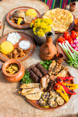 Homemade Romanian Food with grilled meat, polenta and vegetables Platter on camping. Romantic traditional Moldavian food outside on the wood table.