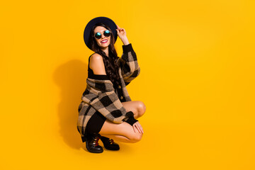 Fototapeta na wymiar Full length profile photo of gorgeous person sit arm touch headwear wear plaid isolated on yellow color background