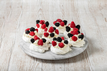 Pavlova's cake on a marble stand. Cake with meringues, raspberries and blackberries. High quality photo