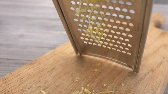 Close-up of a lemon grated on the metal grater into the lemon zest 