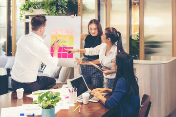 Obraz premium Business people meeting use sticky notes on whiteboard in office. Teamwork diverse employees people group planning work together and success brainstorm strategy.