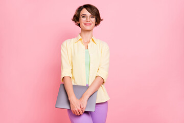 Photo of charming shiny young woman wear yellow shirt glasses holding modern device isolated pink...