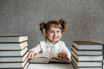Cute kid girl preschooler with glasses, with books at home