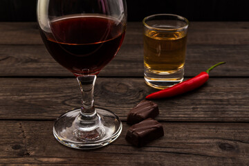 Glass of red wine and tequila with chocolate and cayenne pepper on an old wooden table. Close up...