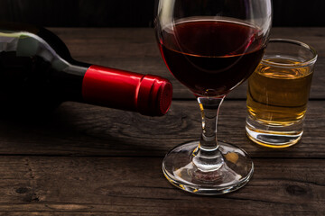 Glass and bottle of red wine and tequila on an old wooden table. Close up view