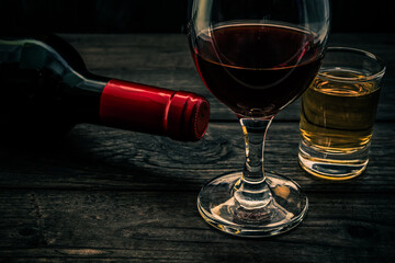 Glass and bottle of red wine and tequila on an old wooden table. Close up view