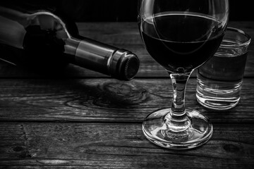 Glass and bottle of red wine and tequila on an old wooden table. Close up view, focus on the glass of red wine