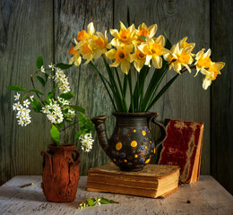 Still life with a bouquet of yellow daffodils, a branch of blooming bird cherry and books. Vintage. Retro.
