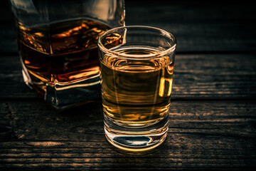 Glass of brandy and tequila on an old wooden table. Close up view, focus on the glass of tequila
