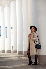a young girl in a hat stands against the background of a building with columns