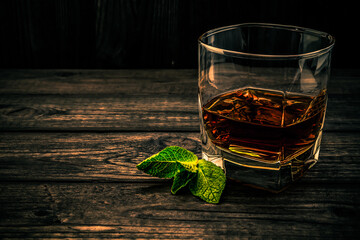 Glass of brandy with mint sprig on an old wooden table. Angle view