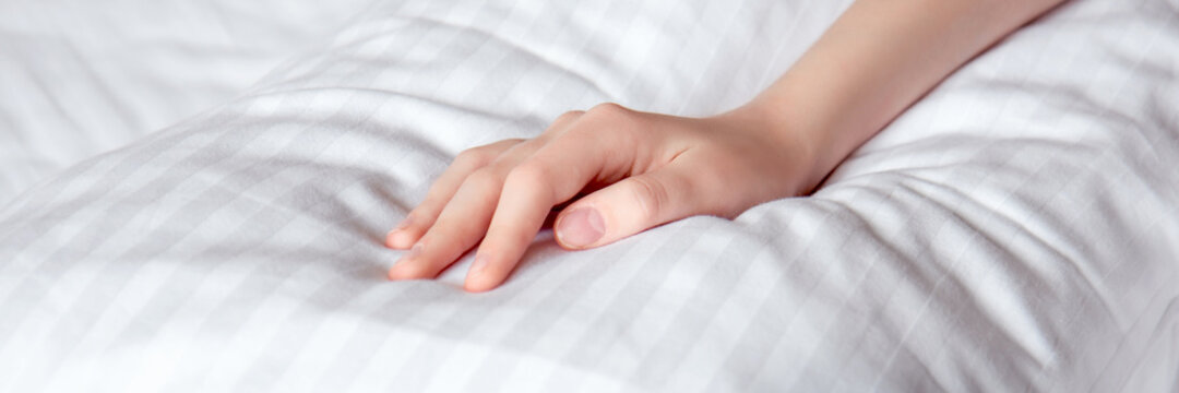 Beautiful female hand on white linens in the rays of the sun. Selective focus. Banner