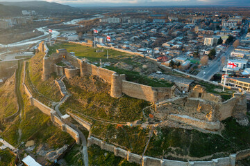 Scenic aerial view of medieval Gori Fortress on hilltop above Georgian city of Gori during spring sunset, Shida Kartli region