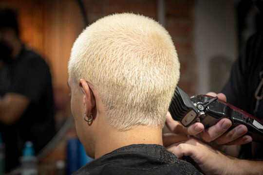 barber's hands cutting and painting head as a young man in vintage barbershop 