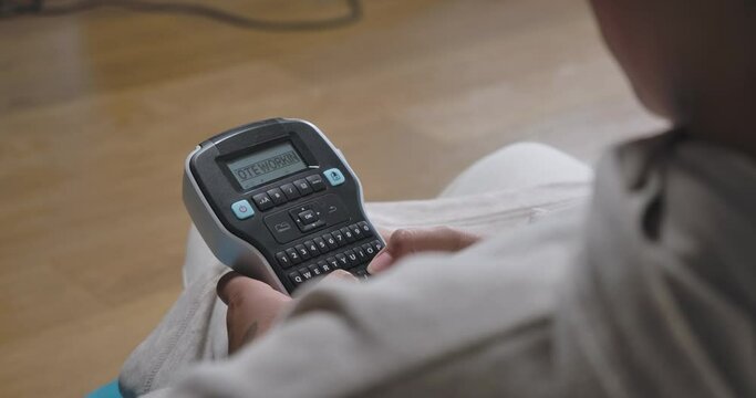 Tattooed African American female hands printing Remote working on label maker. Unrecognizable young woman on remote working in home office indoors. Cinema 4k ProRes HQ