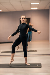 Obraz premium Beautiful young woman is engaged in gymnastics in the gym. The athletic body of the girl is covered with tight-fitting yoga clothes.