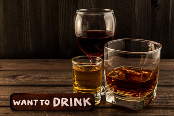 Three glasses with brandy, tequila and red wine with the wooden plank on it is an inscription 