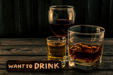 Three glasses with brandy, tequila and red wine with the wooden plank on it is an inscription 