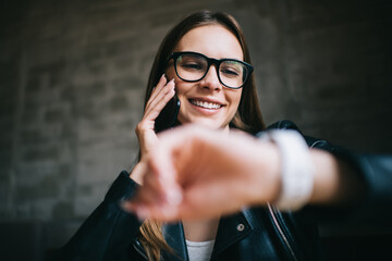 Cheerful Caucaisan woman in stylish eyewear for vision protection enjoying friendly cellphone...