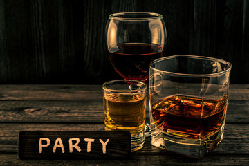 Three glasses with brandy, tequila and red wine with the wooden plank on it is an inscription 