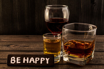 Three glasses with brandy, tequila and red wine with the wooden plank on it is an inscription 