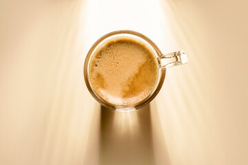 coffee cup with cream coffee, top view on background with sunlight.