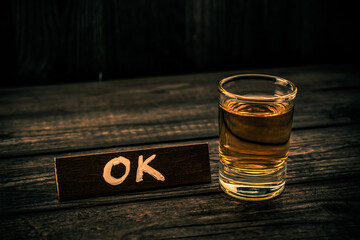 Glass of tequila with the wooden plank on it is an inscription 