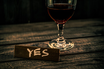 Glass of red wine with the wooden plank on it is an inscription 