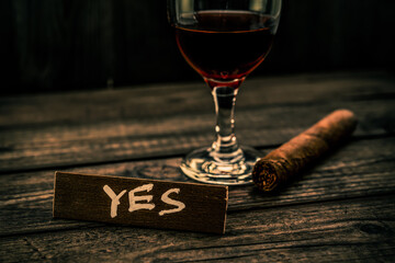 Glass of red wine with cuban cigar and the wooden plank on it is an inscription 