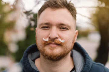 Man with white flowers in mustache. Breathe free