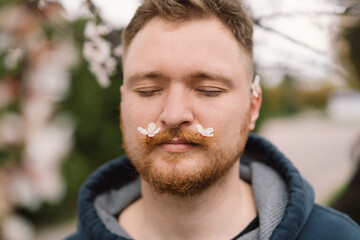 Fototapeta premium Man with white flowers in mustache. Breathe free