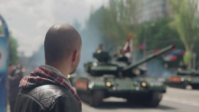 A man watches tanks moving through the city during a military parade