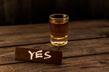 Glass of tequila with the wooden plank on it is an inscription 