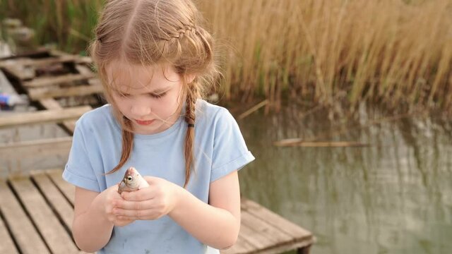 little girl holding fish that she had just caught in river.fishing with children