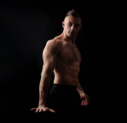 Fototapeta na wymiar Powerful strong sport man with muscular bodybuilder looking and holding his arm muscle tension on black dark background. Closeup