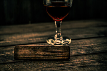 Glass of red wine with the empty wooden plank on an old wooden table. Angle view, focus on the wooden plank