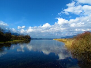 Scenic view of beautiful lake Cerknica or Cerknisko jezero in Notranjska region of Slovenia with white clouds in blue sky and a reflection in the lake