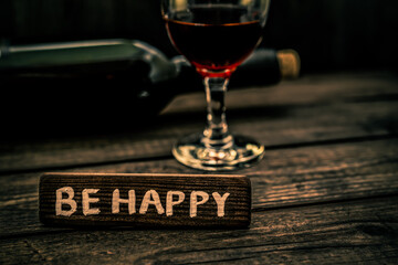 Glass and bottle of red wine with the wooden plank on it is an inscription 