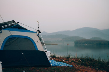 Camping tent on the camping area near the lake among the mountain and fog
