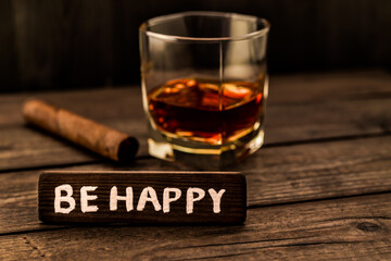 Glass of brandy with cuban cigar and the wooden plank on it is an inscription 