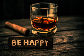 Glass of brandy with cuban cigar and the wooden plank on it is an inscription 