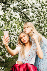 Obraz premium Girl, daughter with mother, blooming Apple trees, trees, flowers, branches, spring, summer, beauty, nature, communication, family, kiss, meeting, read a book, talk